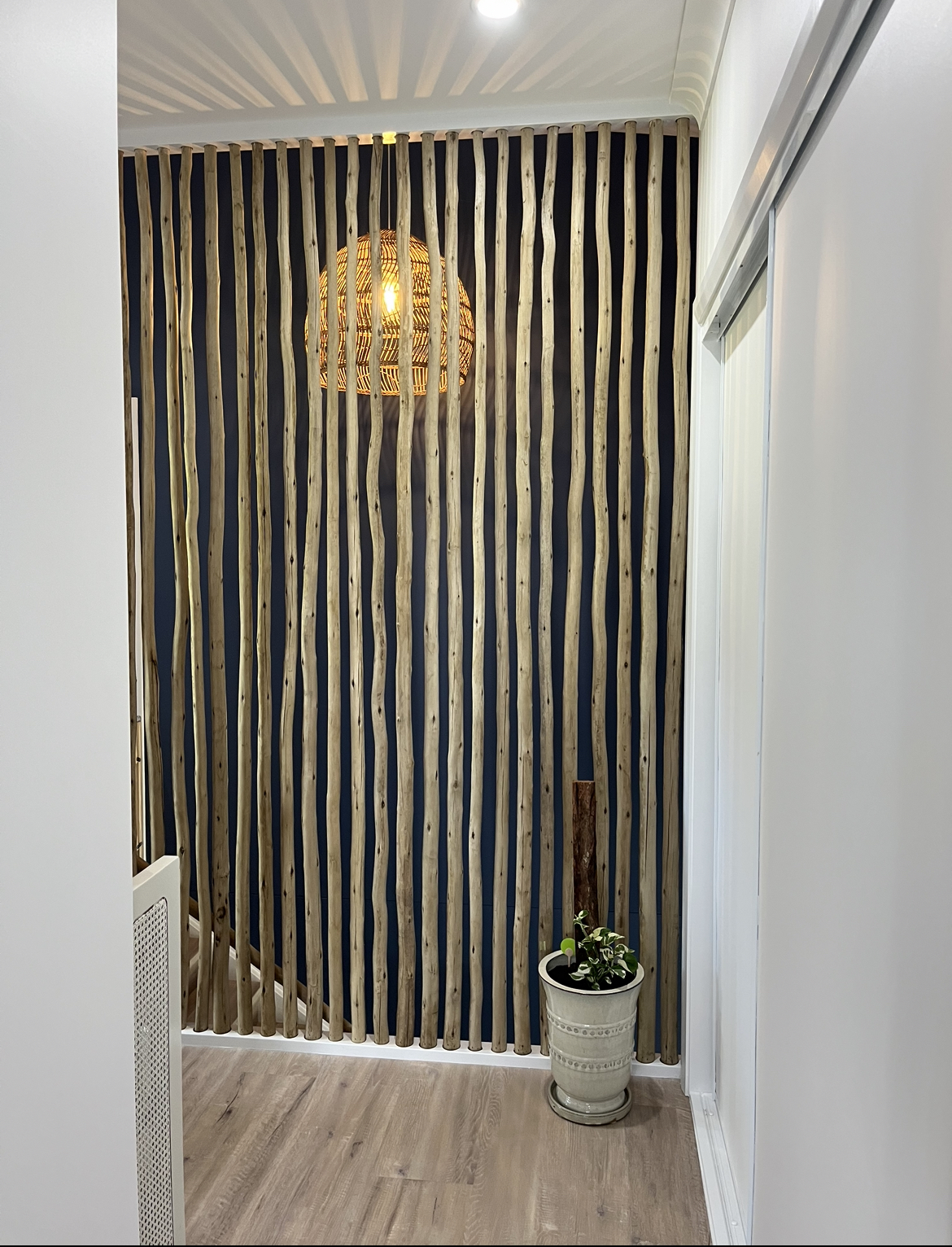 Timber batten feature wall lit by downlights with a woven pendant light